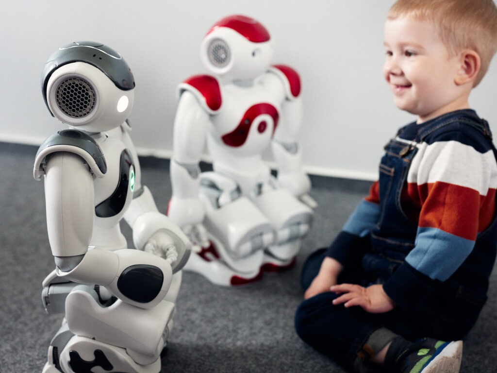 A happy child playing with two small robots